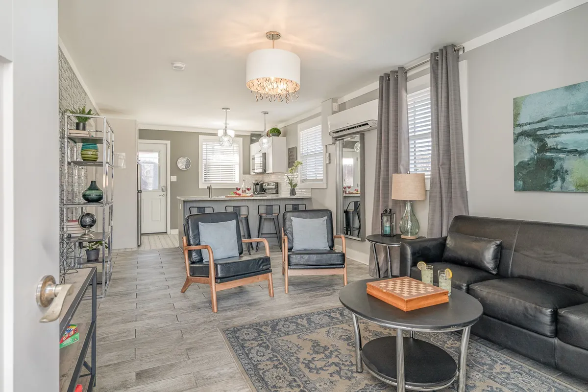 A stylish living room with a comfy sofa, coffee table, inviting armchairs, warm lighting, and artwork on the wall. The open, accessible arrangement encourages group activities like board games or relaxed conversations, while the decor adds a welcoming touch.