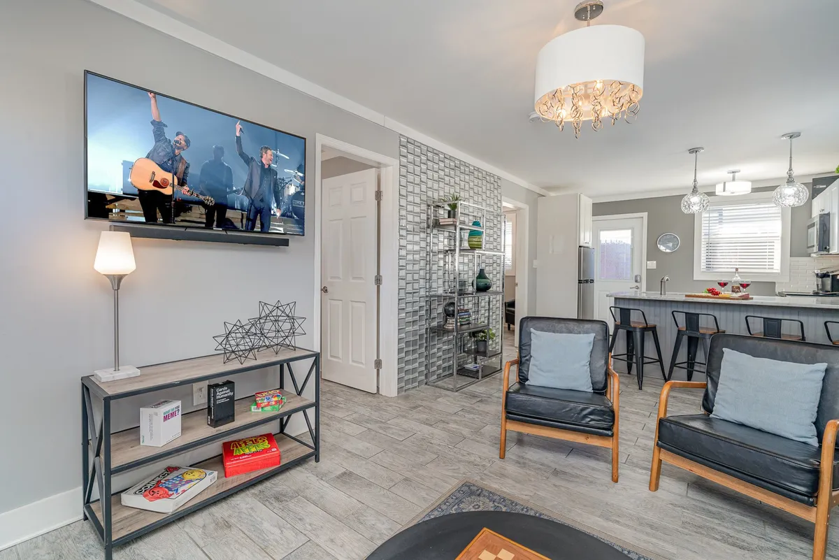 A modern interior space featuring a television mounted above a decorative shelving unit, with comfortable chairs grouped around it. Decorative lighting and contemporary styling give the room a fresh, lively atmosphere suited for entertainment and downtime.