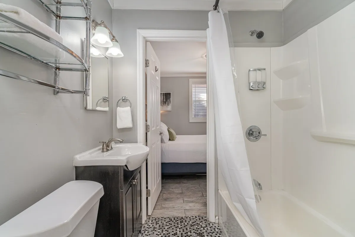A modern bathroom with a sleek sink, shower, toilet, and mirror, bathed in calming light. The contemporary fixtures and soft color palette evoke a spa-like, relaxing environment.