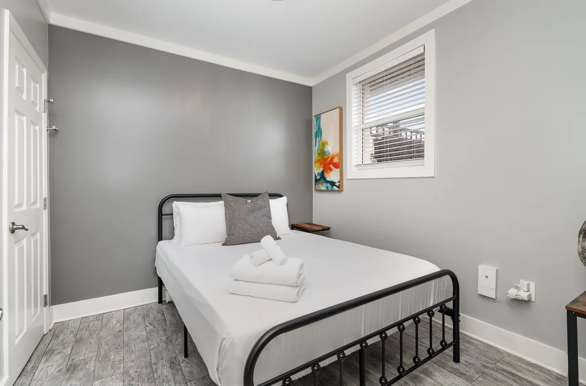 A peaceful bedroom highlighted by a comfortable bed, elegant artwork above the headboard, and a well-placed nightstand, all contributing to a restful and creative ambiance.